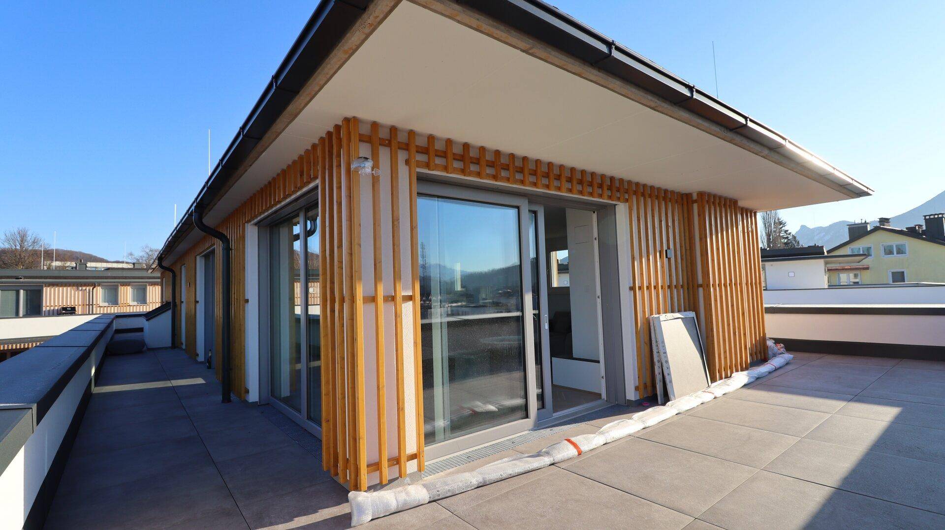 Große Dachterrasse mit Holzlamellenfassade und Schiebetüren zu den Innenräumen.