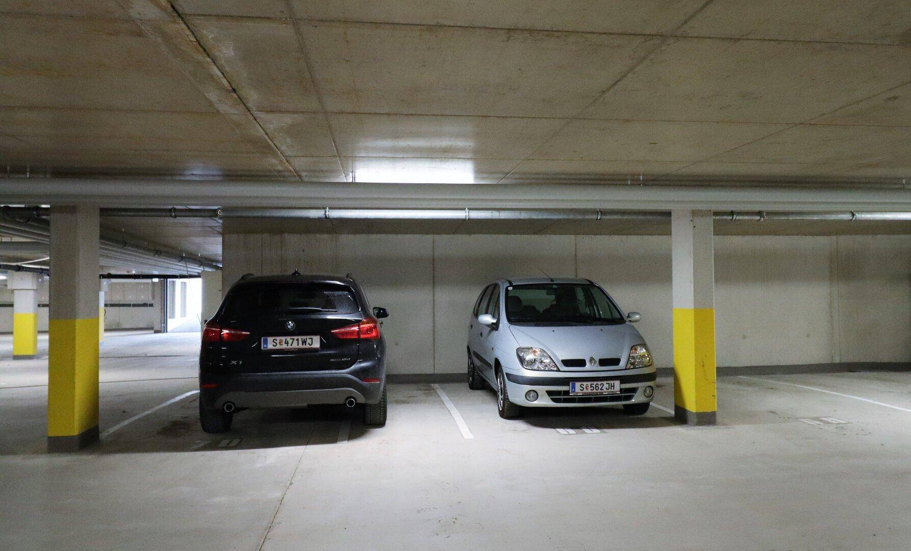Tiefgarage mit zwei geparkten Autos und Betonwänden.