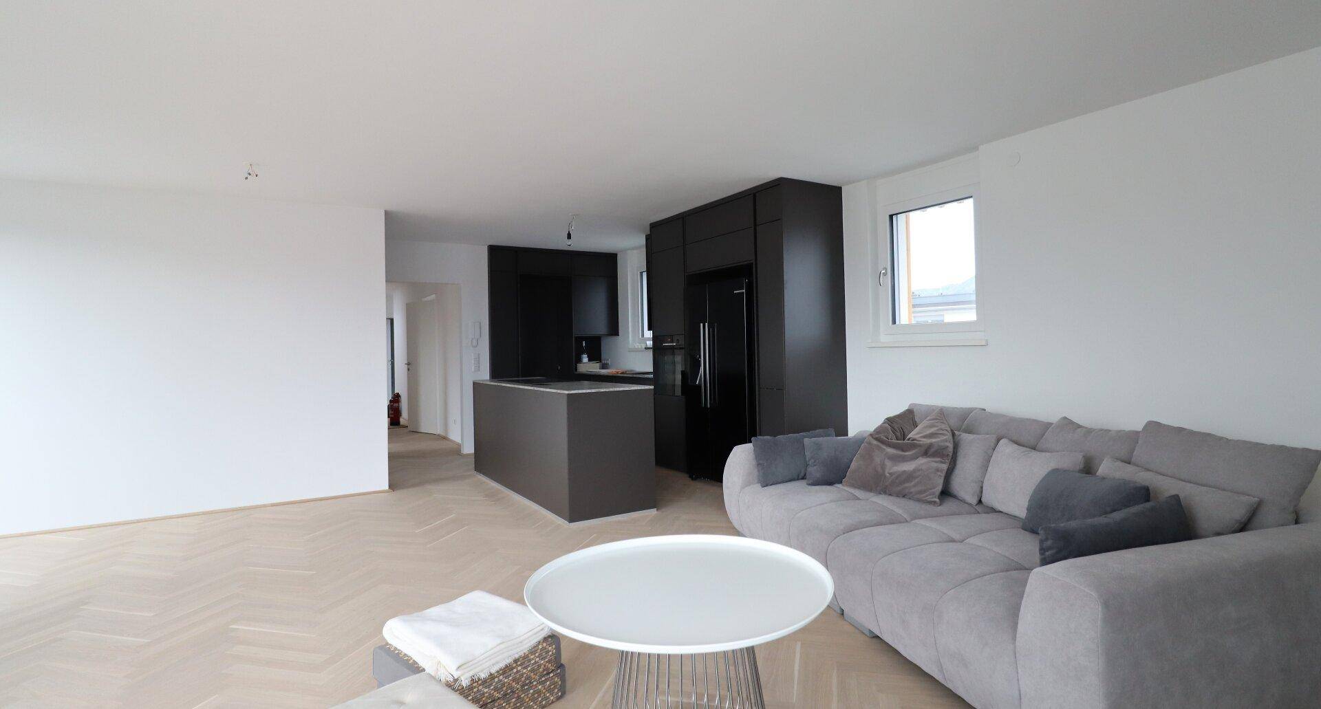 Heller offener Wohnbereich mit moderner Küche und gemütlichem Sofa.