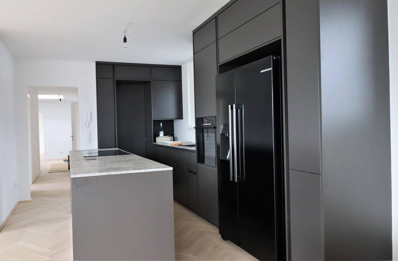 Moderne schwarze Einbauküche mit Kücheninsel und integrierten Geräten.