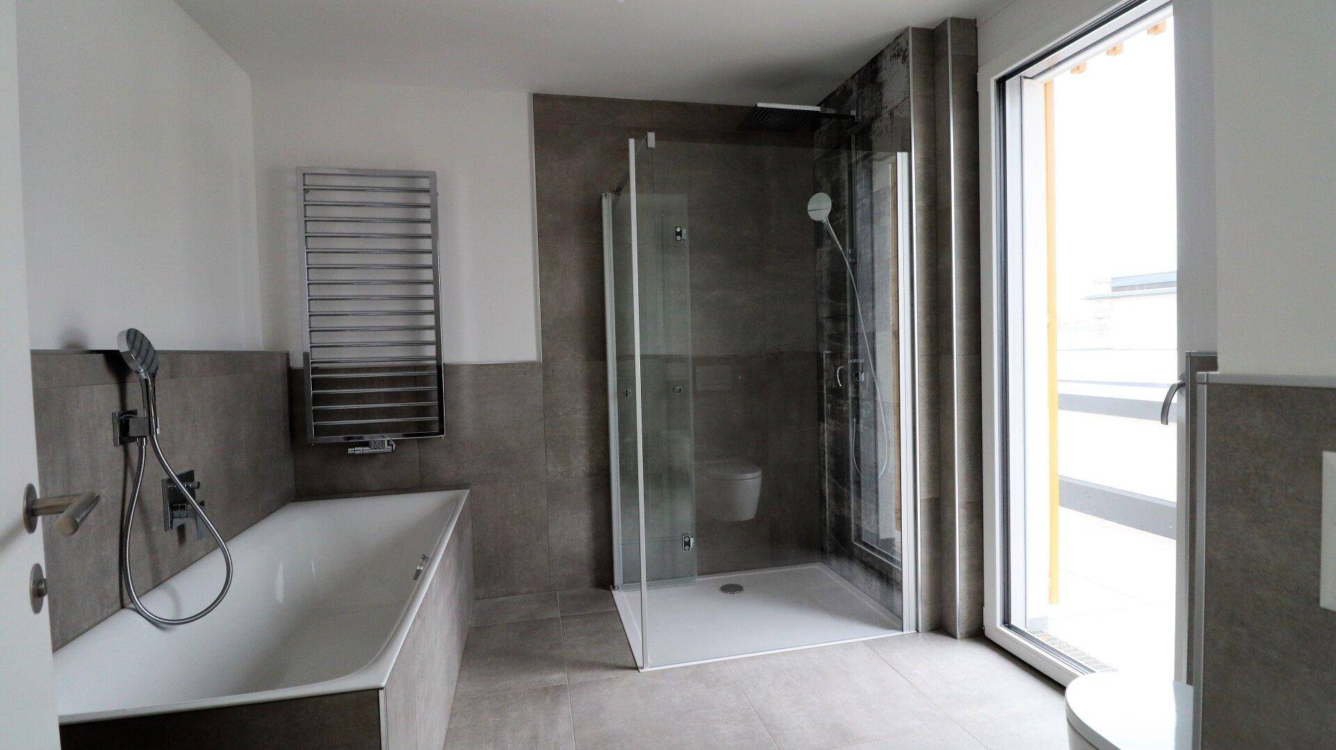 Modernes Badezimmer mit Badewanne, ebenerdiger Dusche und beheiztem Handtuchhalter.