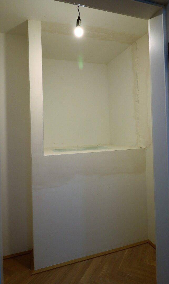 Kleiner, leerer Abstellraum oder begehbarer Schrank mit einfacher Beleuchtung.