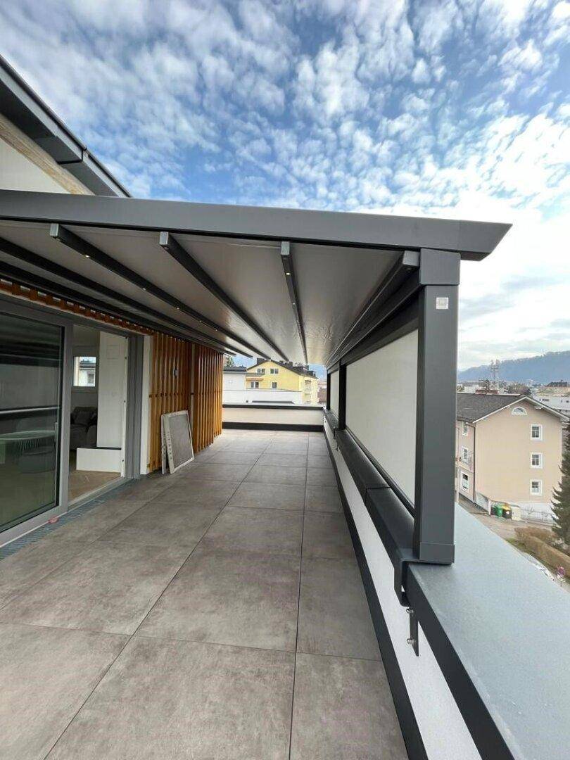 Überdachte Dachterrasse mit moderner Pergola und Blick auf die umliegende Bebauung.