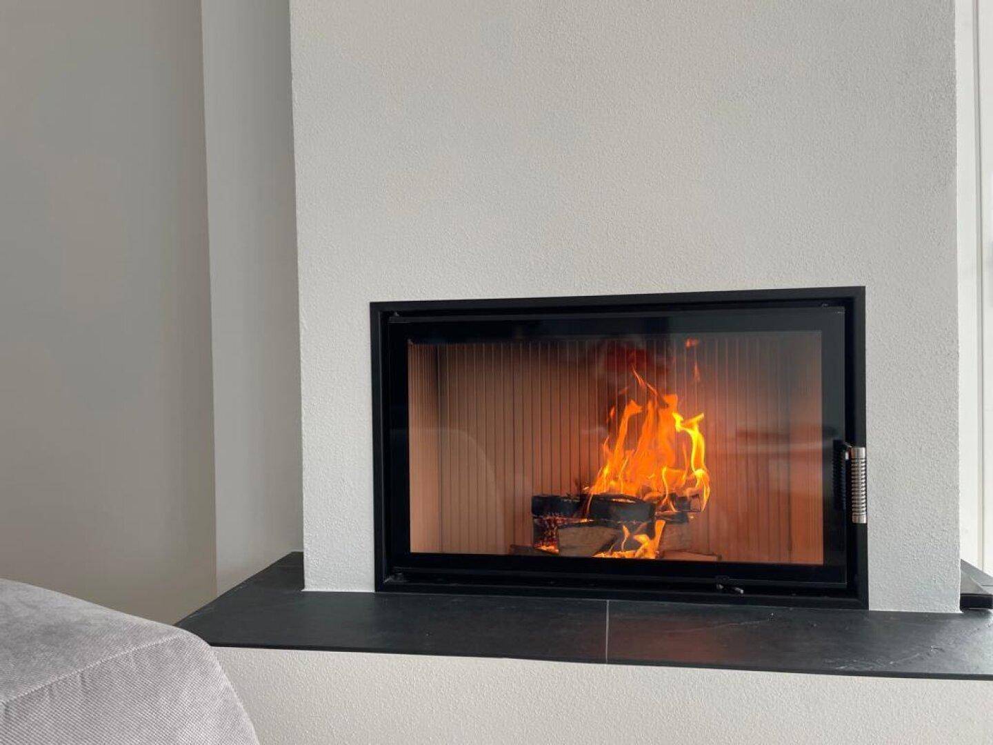 Nahaufnahme eines modernen Kamins mit brennendem Holz, der Wärme und Atmosphäre spendet.