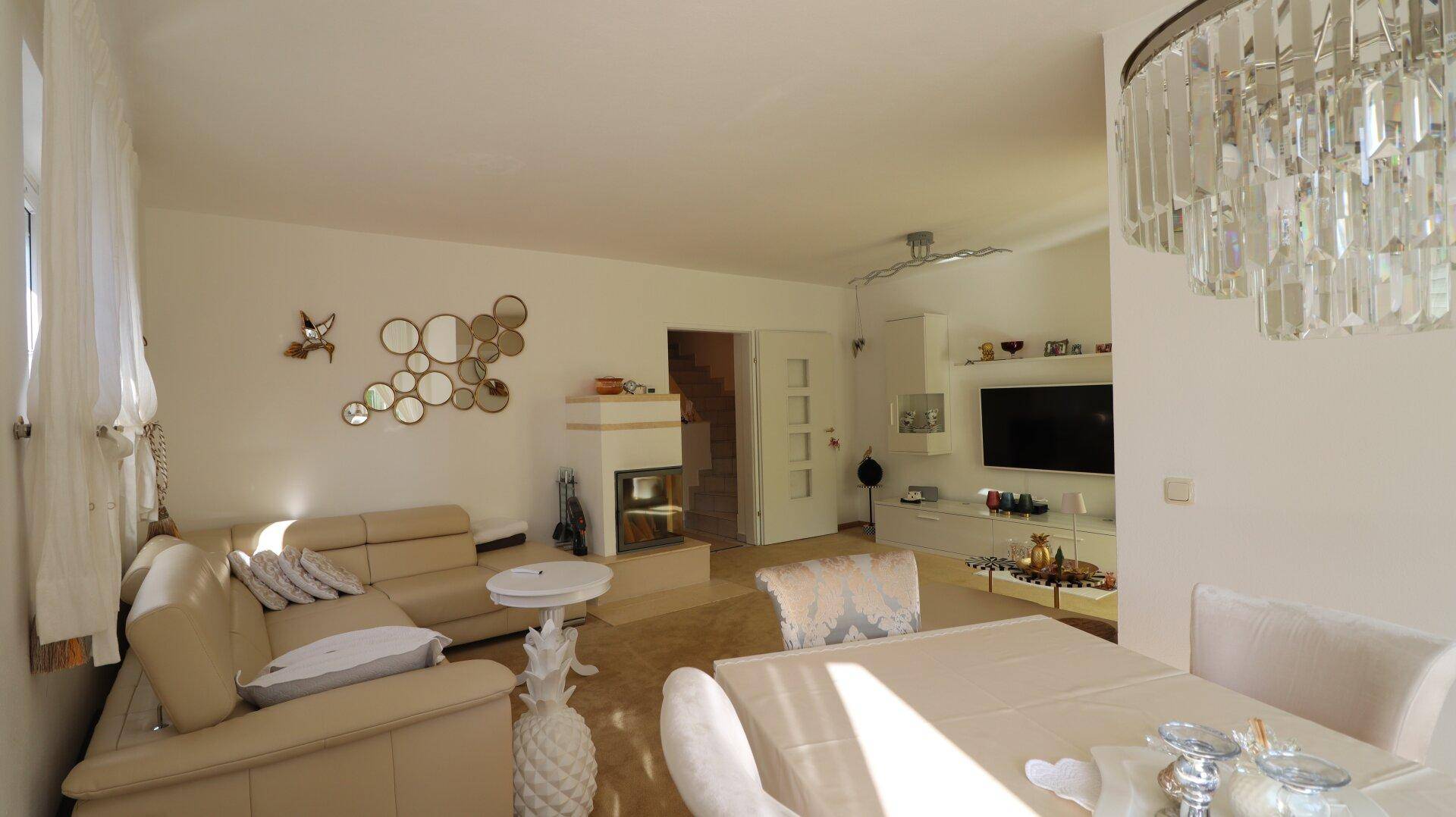 Lichtdurchfluteter Wohn- und Essbereich mit elegantem Kronleuchter und modernem Dekor.