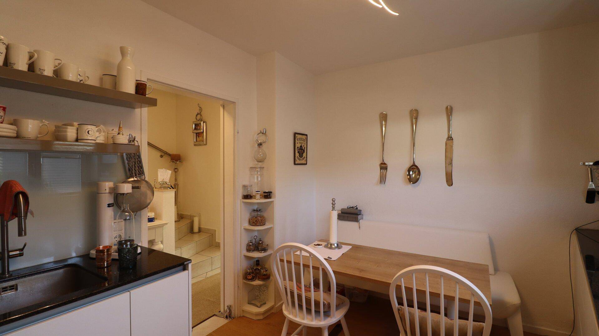 Essbereich in der Küche mit Holztisch, Sitzbank und Blick zum Flur.