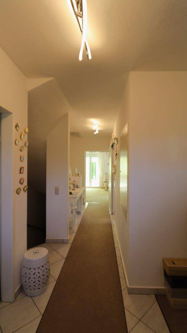 Langer, heller Flur mit Teppichläufer und Blick auf den Eingangsbereich.