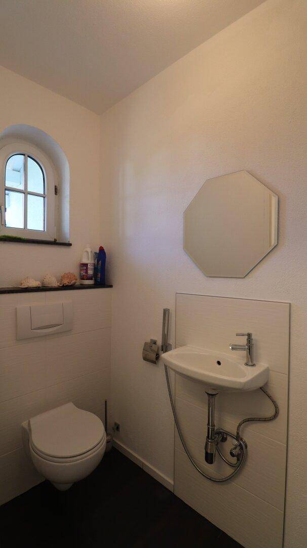 Kleines Gäste-WC mit Fenster, Wand-WC und modernem Waschbecken.