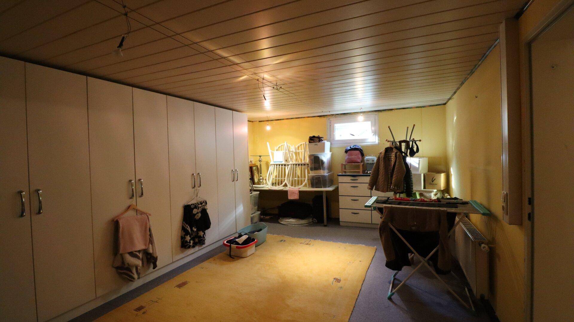 Kellerraum mit Schränken, Lagerfläche und kleinem Fenster.