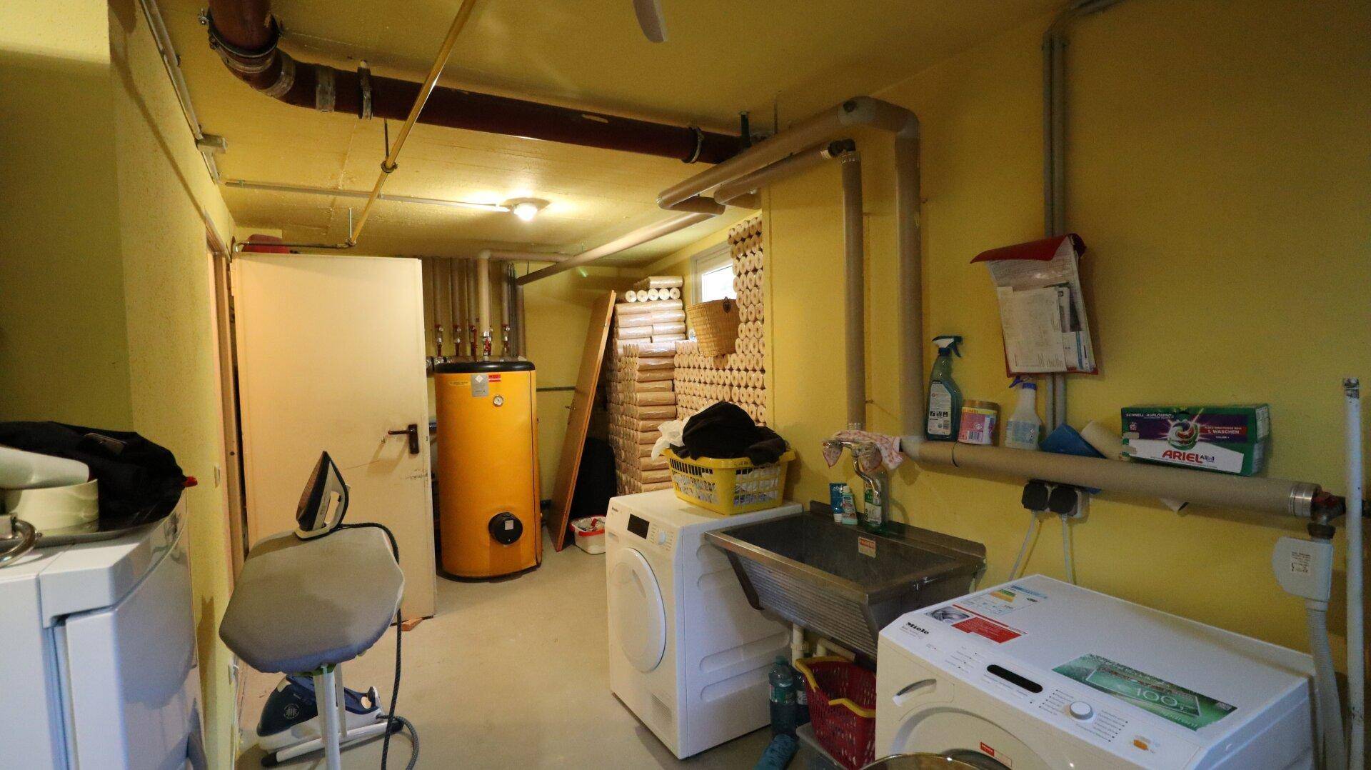 Waschküche im Keller mit Waschmaschinen, Trockner und Warmwasserspeicher.