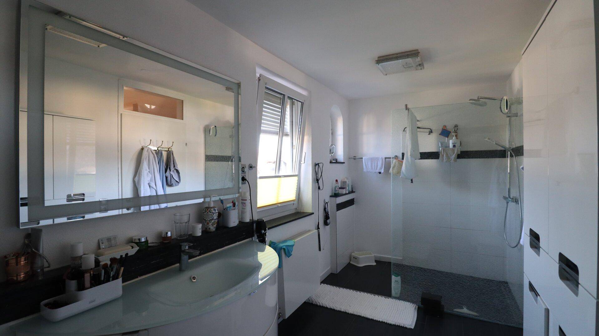 Modernes Badezimmer mit großer Dusche, Doppelwaschbecken und Fenster.