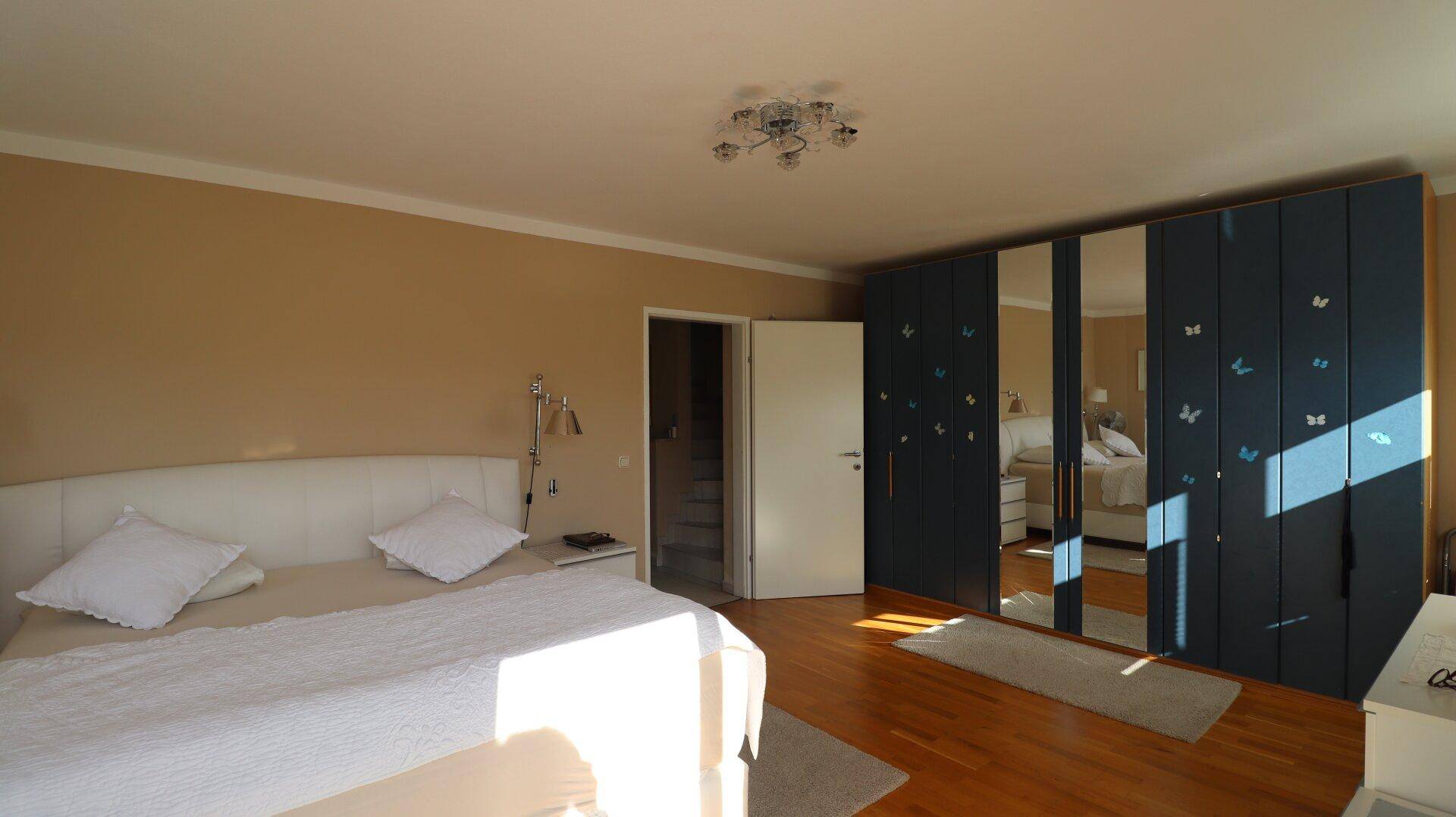 Schlafzimmer mit großem Kleiderschrank, Doppelbett und Holzboden.