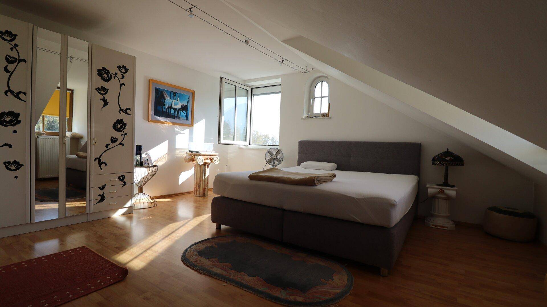 Schlafzimmer im Dachgeschoss mit Holzboden, Schrägen und großem Kleiderschrank.