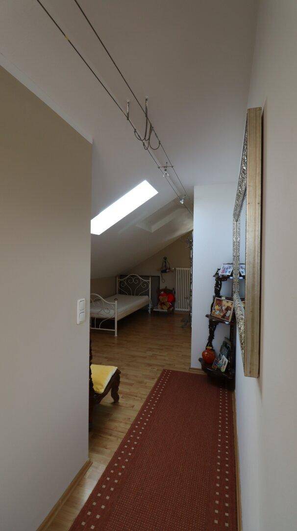 Flur im Dachgeschoss mit Teppichläufer, Dachfenster und Zugang zu weiteren Räumen.