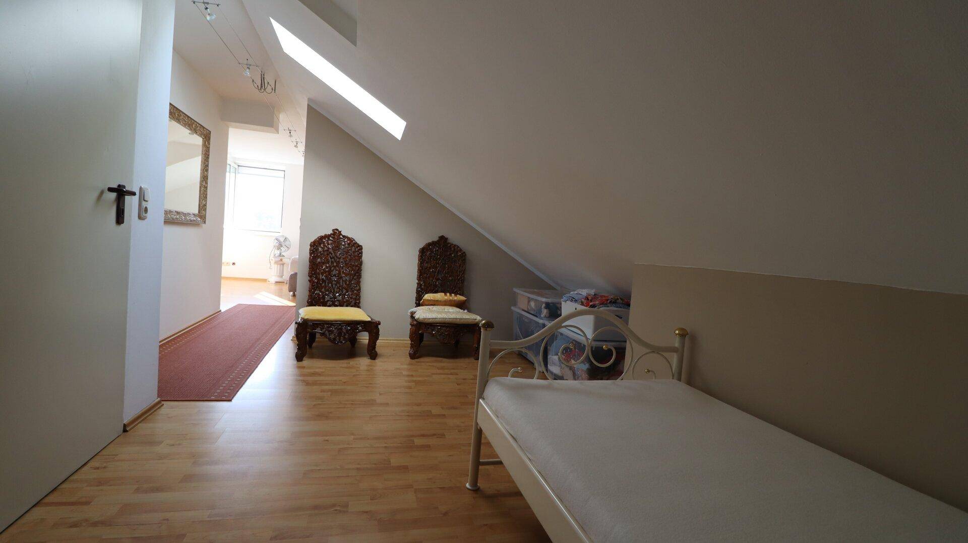 Dachgeschosszimmer mit Holzboden, Schrägen und Einzelbett.