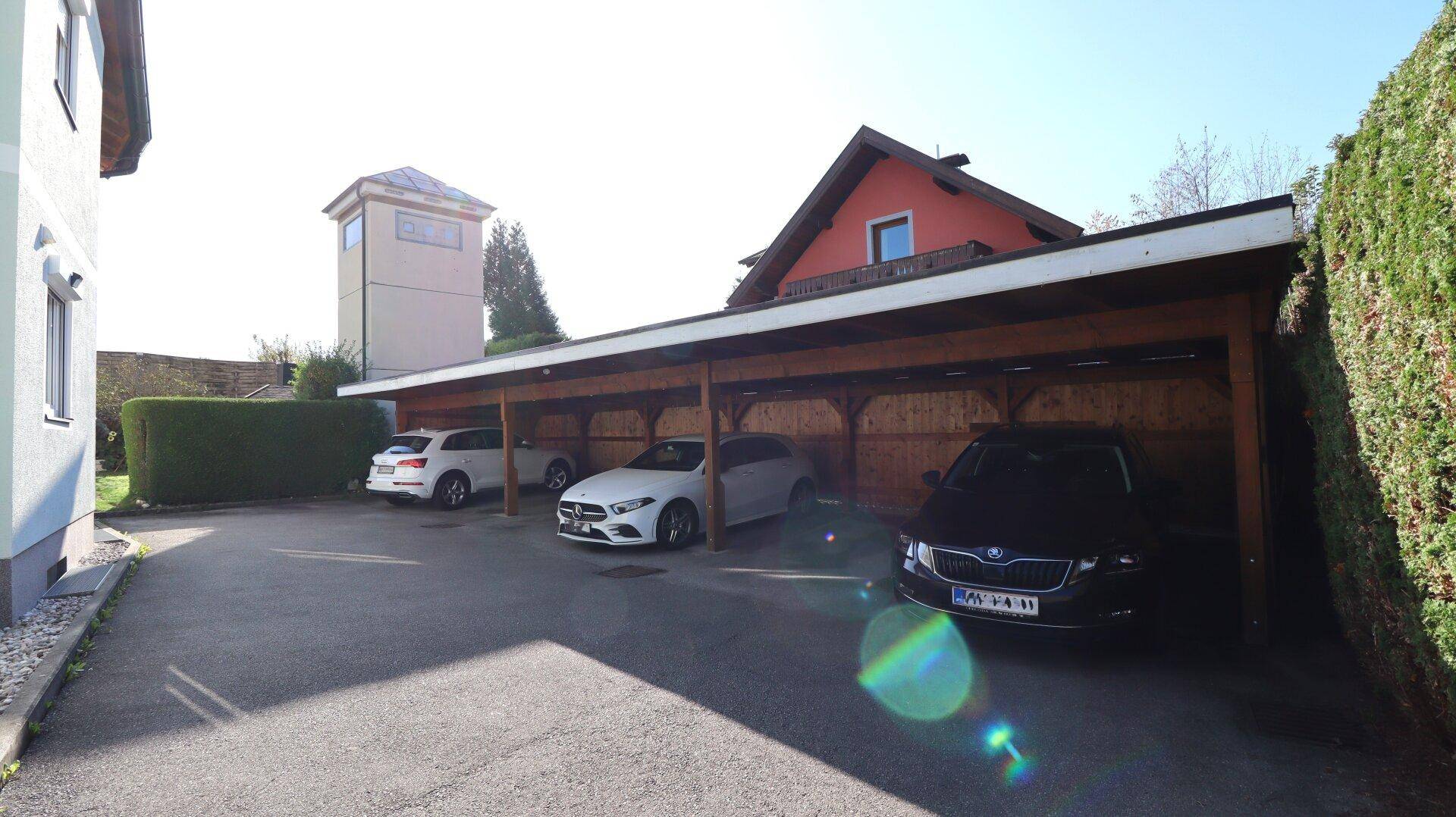 Überdachter Parkplatz für mehrere Fahrzeuge neben dem Haus.
