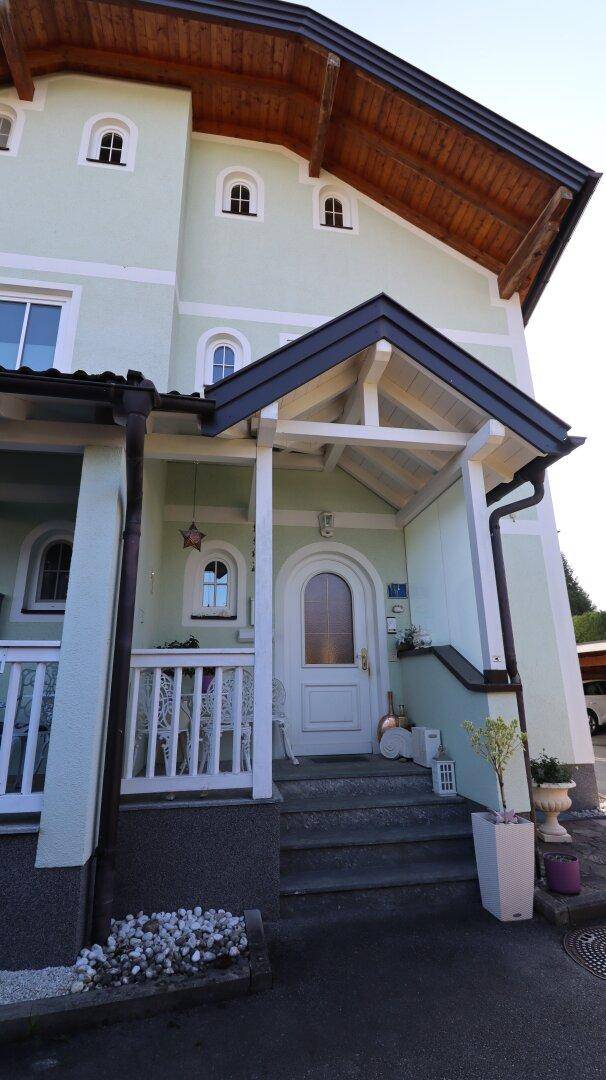 Eingangsbereich des Hauses mit überdachtem Vordach, Treppe und Bogenfenstern.