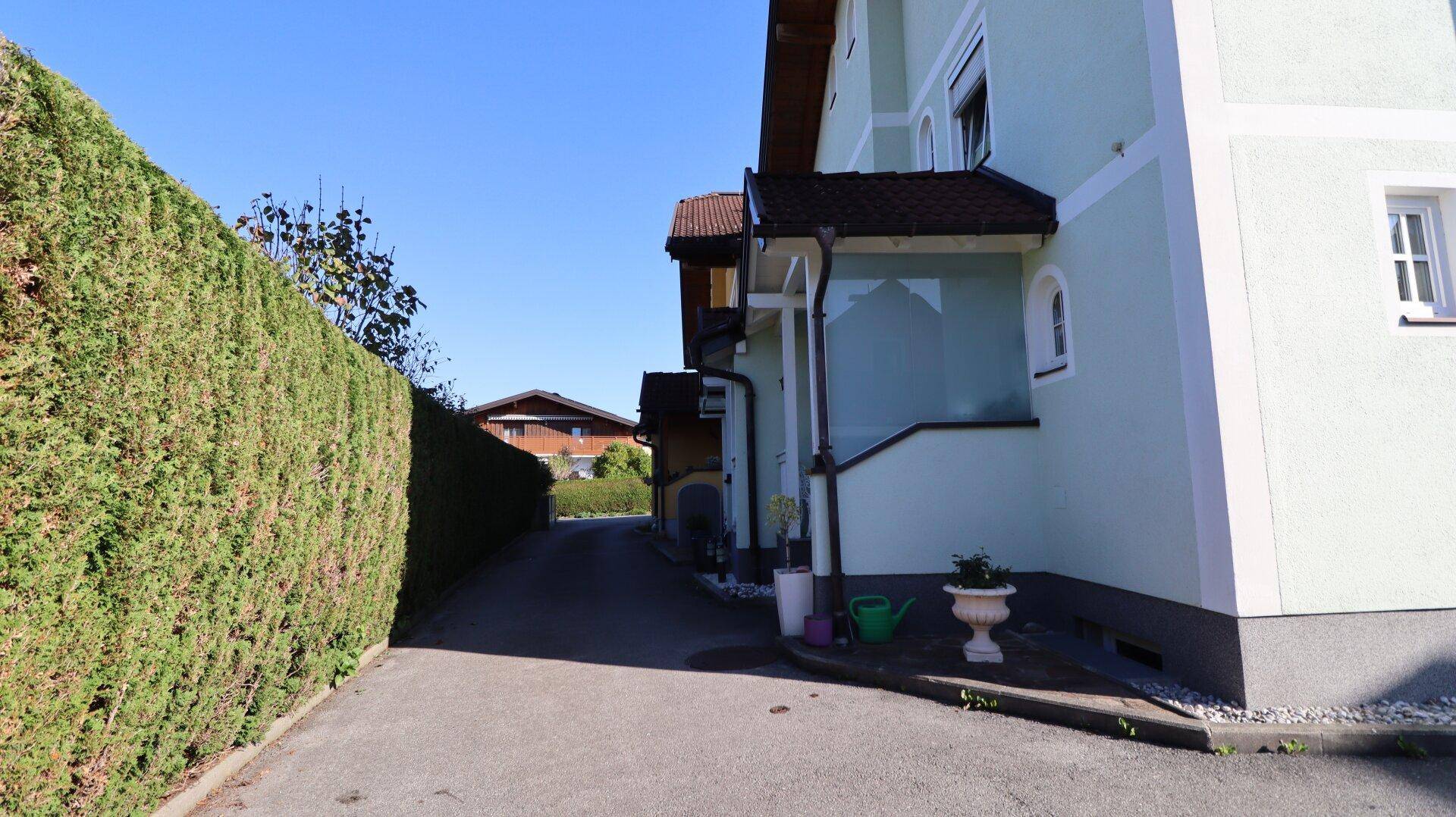 Zufahrt zum Haus mit hoher Hecke und Blick auf die Umgebung.