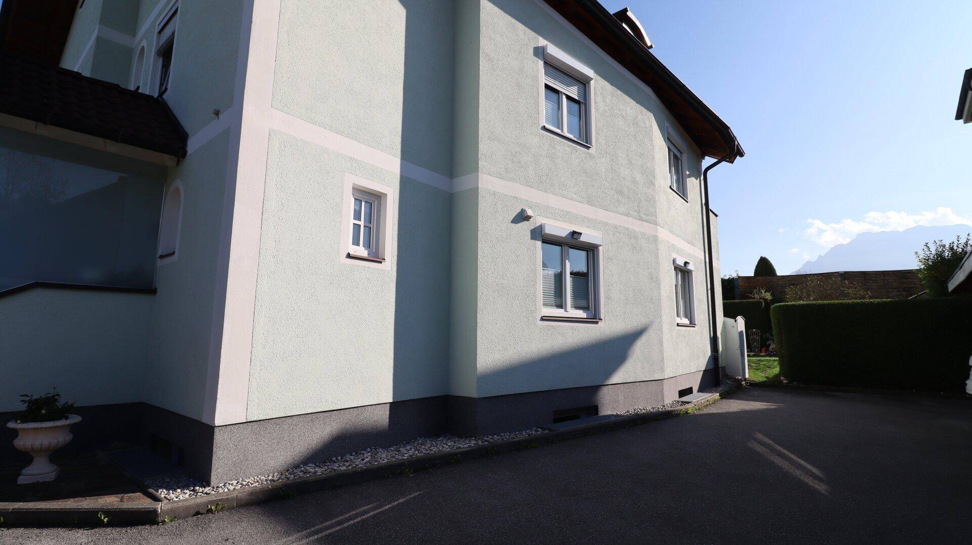 Seitenansicht des Hauses mit Fenstern und gepflegter Fassade.