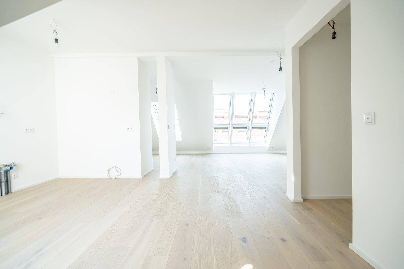 Geräumiger, heller Wohnbereich im Dachgeschoss mit Holzboden und großen Dachfenstern.