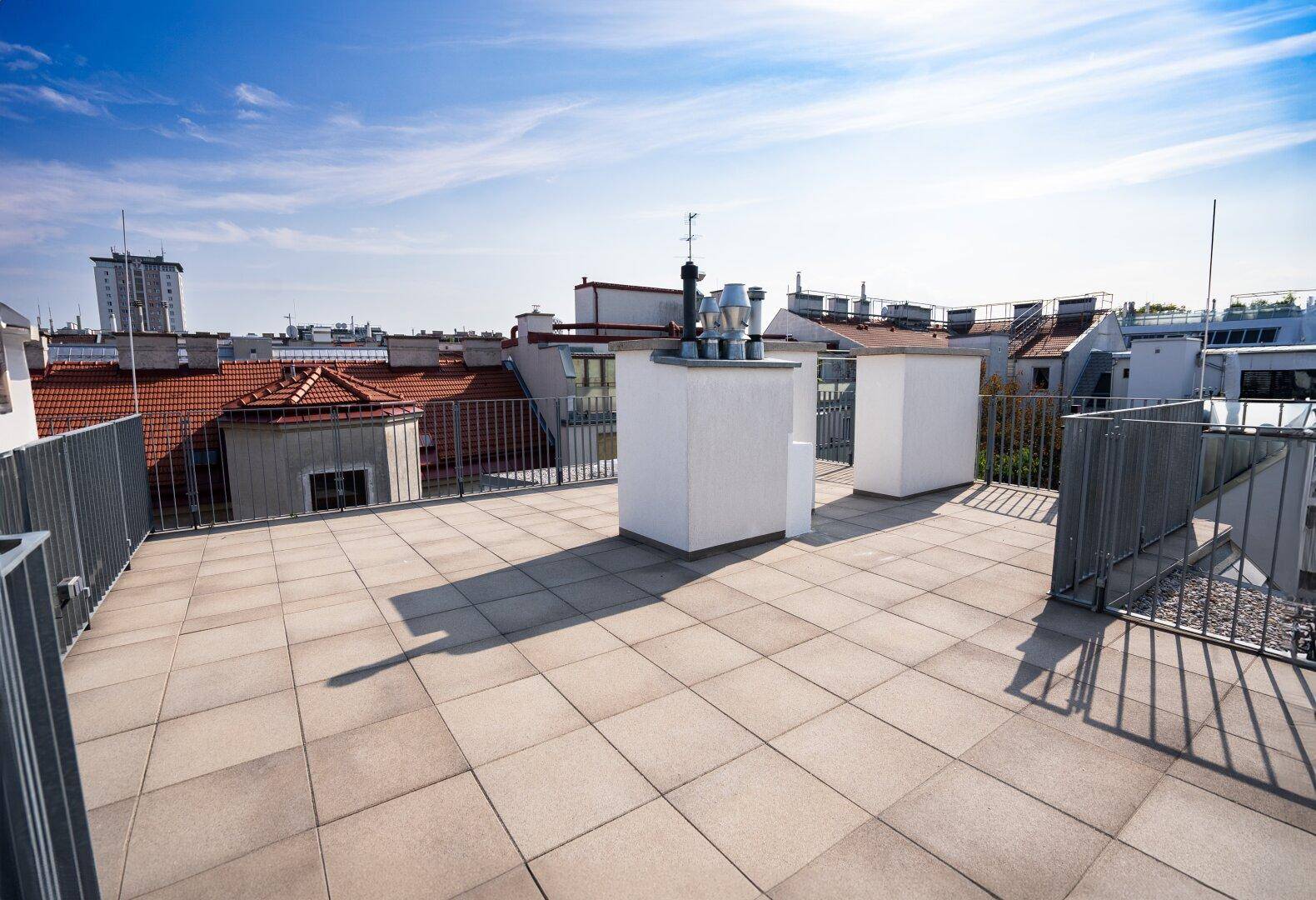 Geräumige Dachterrasse mit hellen Fliesen und Metallgeländer, ideal für Entspannung im Freien.