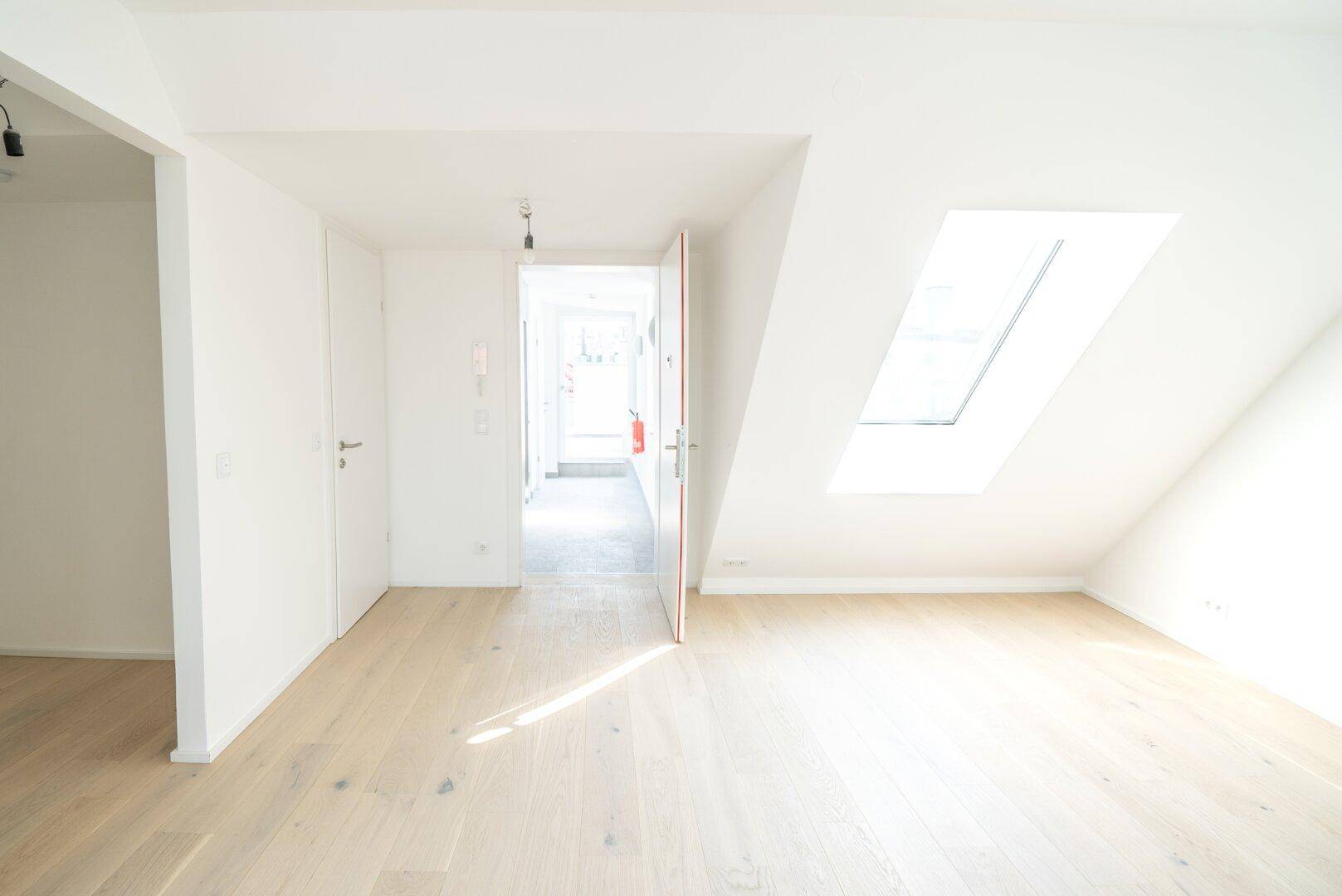 Heller Eingangsbereich mit Holzboden und Dachfenster, der zu den Wohnräumen führt.