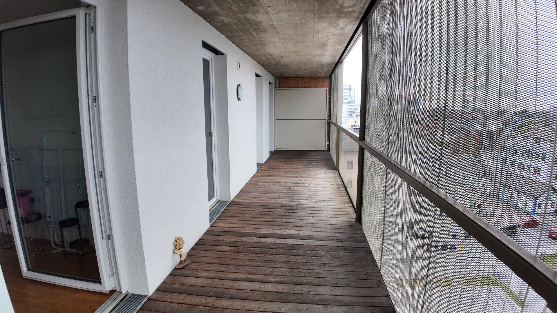Langer Balkon mit Holzfußboden und Metallgeländer, bietet einen weiten Ausblick.