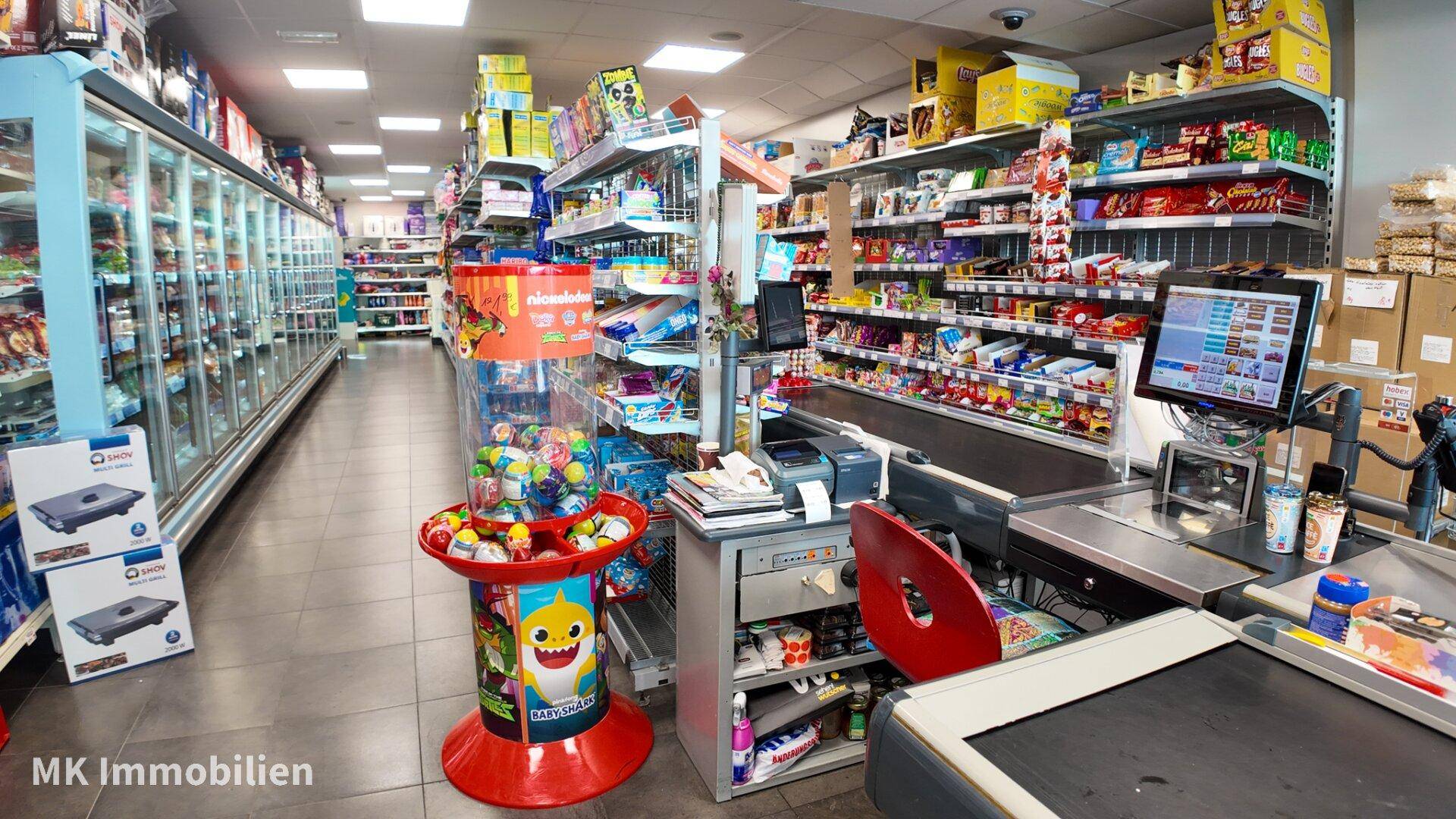 Kassenbereich und Tiefkühlabteilung eines Supermarktes mit breiten Gängen und gut sortierten Regalen.