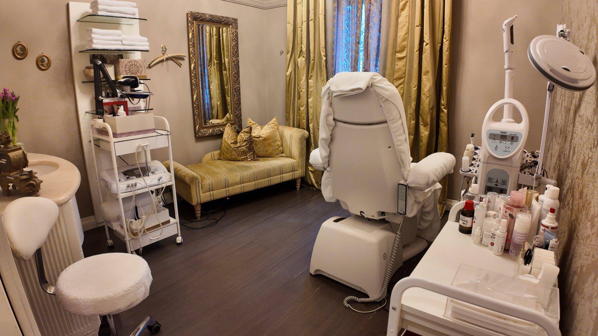 Luxuriöser Behandlungsraum mit einem Therapiesessel, einer Chaiselongue und einem Schminktisch.