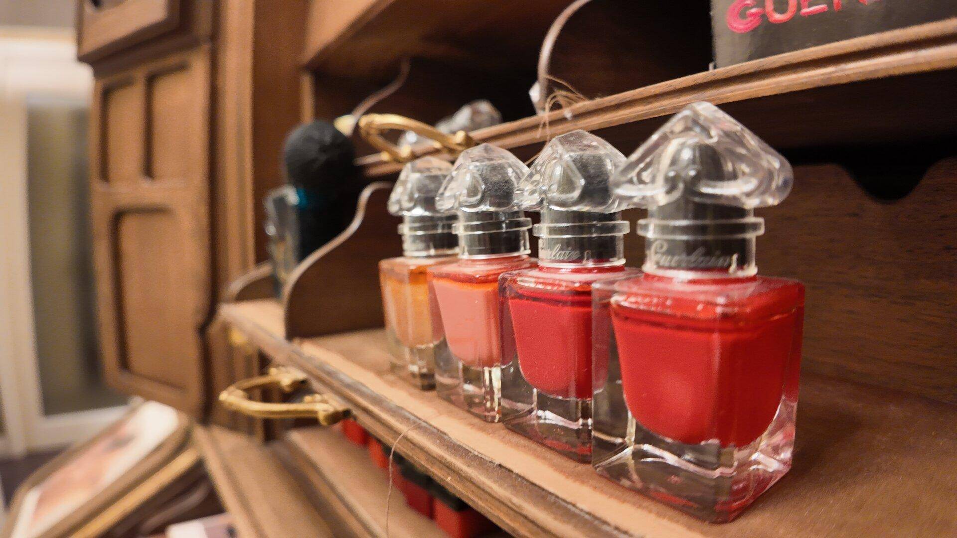 Nahaufnahme von Nagellackflaschen in verschiedenen Rottönen auf einem Holzregal.
