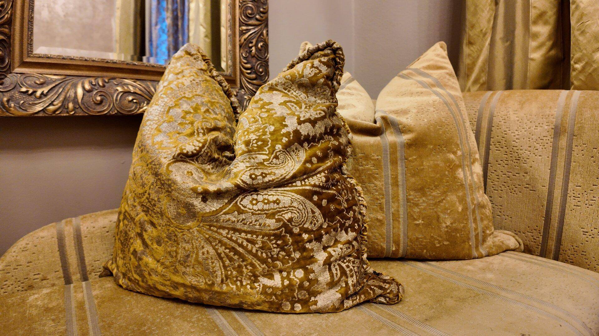 Nahaufnahme von dekorativen Kissen mit goldenem Muster auf einem Sofa.
