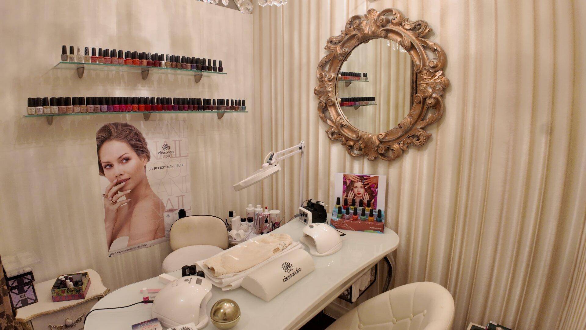 Nagelstudio-Arbeitsplatz mit einem Tisch, Stuhl und Regalen voller Nagellackflaschen.