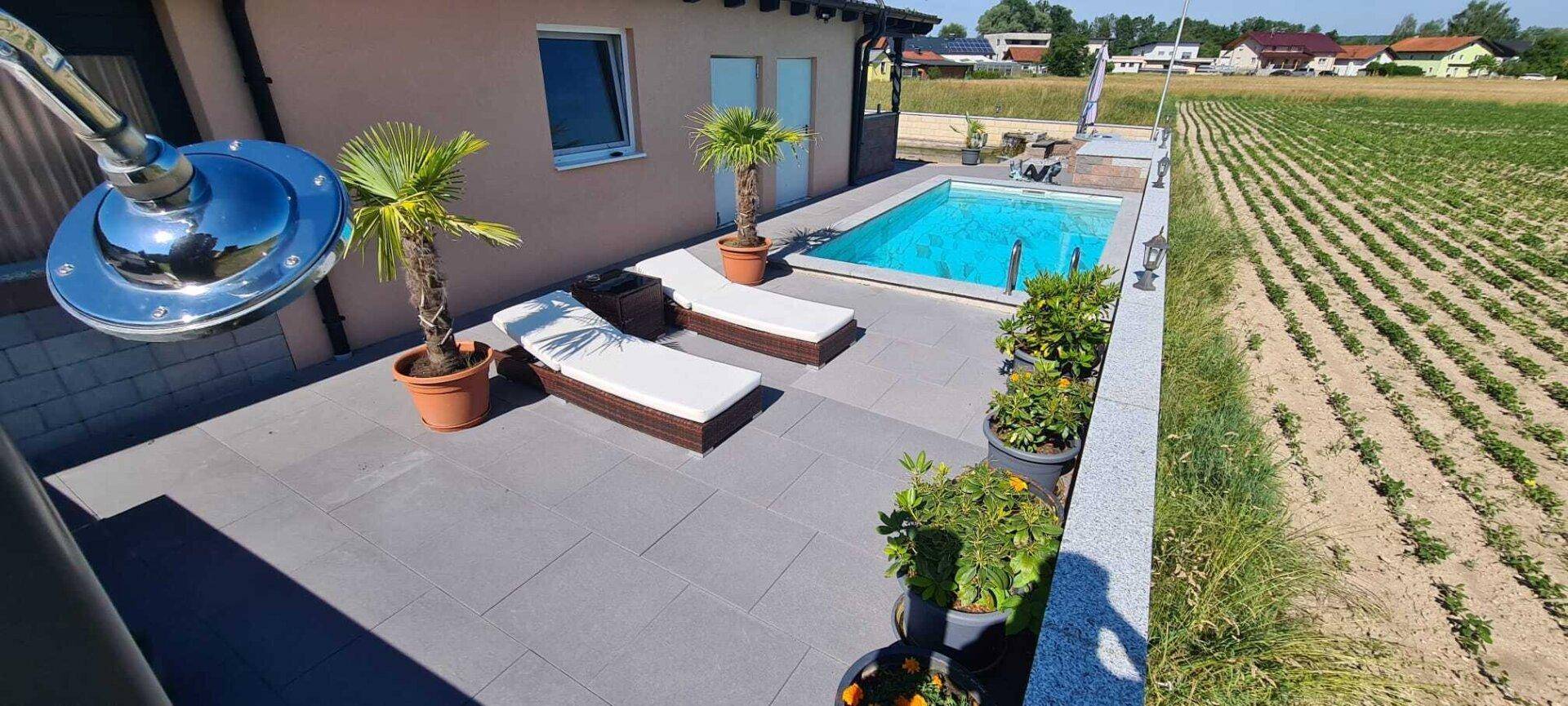 Sonniger Poolbereich mit Liegestühlen und Blick auf die weiten Felder.