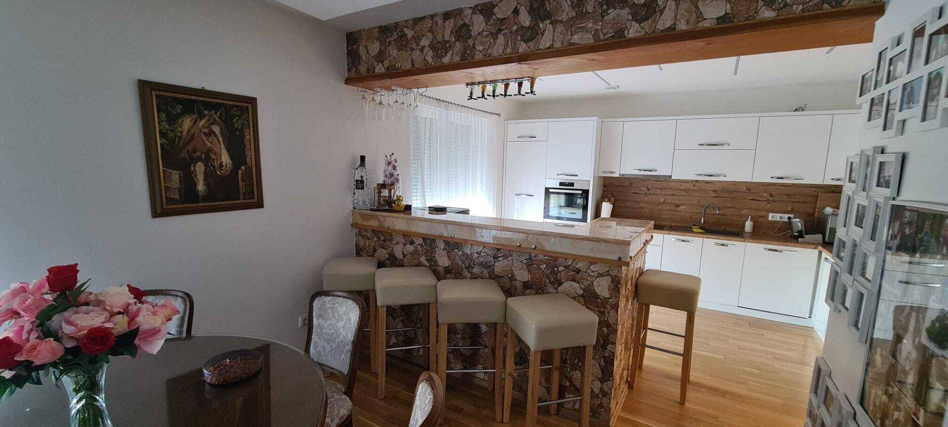 Offene Küche mit Frühstücksbar, Essbereich und Holzboden.
