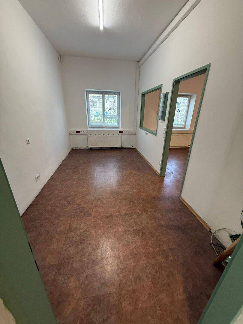 Heller, leerer Raum mit Linoleumboden und Fenstern, der vielseitig genutzt werden kann.