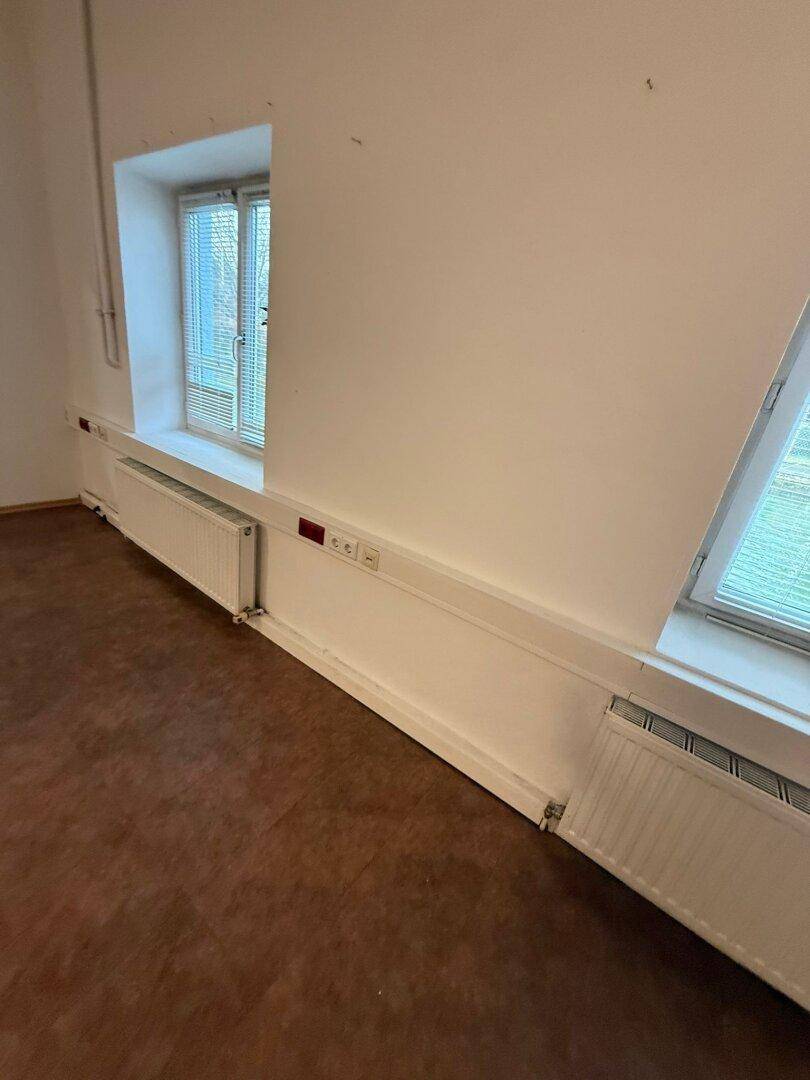 Nahaufnahme von Fenstern und Heizkörpern in einem leeren Raum mit weißen Wänden.