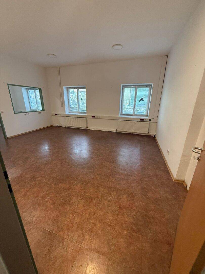 Heller, leerer Raum mit Linoleumboden und zwei Fenstern, ideal für gewerbliche Nutzung.