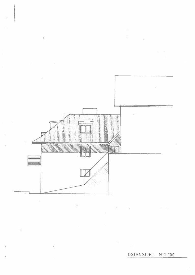 Ostansicht des Gebäudes mit schrägen Dächern und verschiedenen Fenstergrößen.
