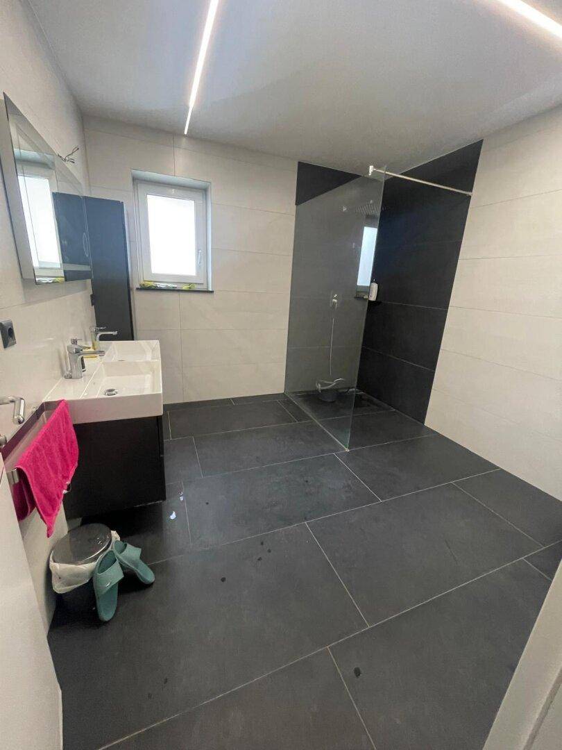 Modernes Badezimmer mit Doppelwaschbecken, großer begehbarer Dusche und Fenster.
