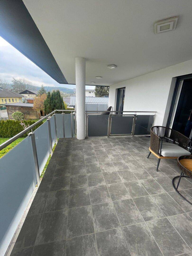 Geräumiger Balkon mit Fliesenboden, Sitzgelegenheiten und weitem Ausblick auf die Umgebung.