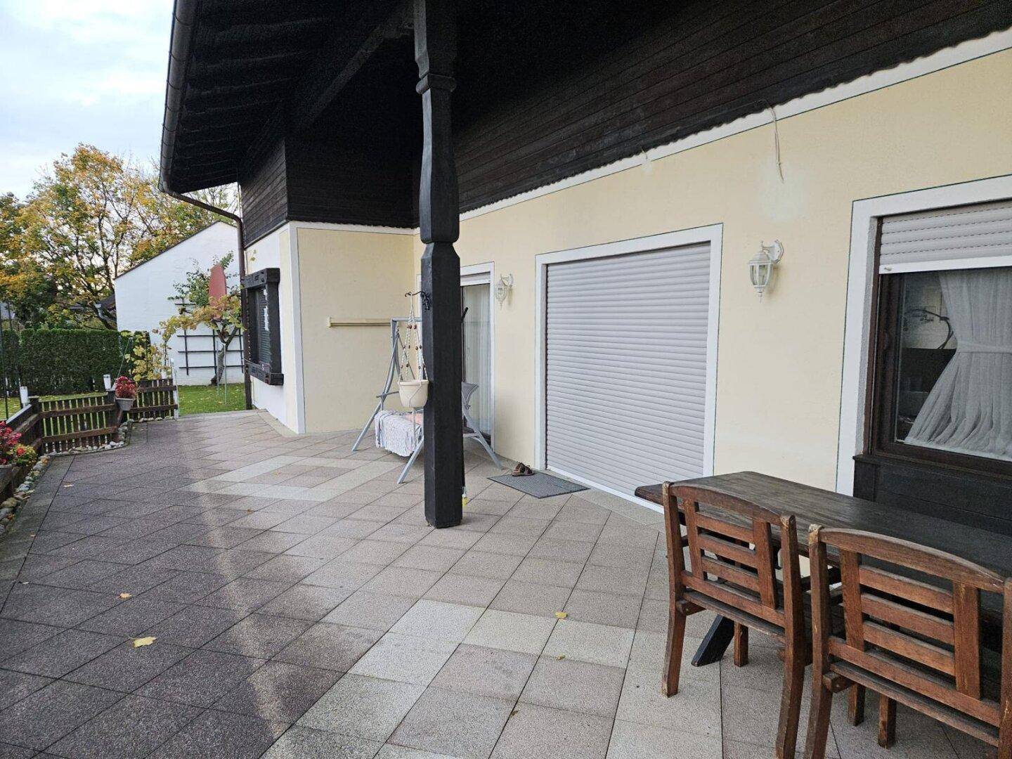 Geräumige gepflasterte Terrasse mit Holztisch und Stühlen, ideal für Mahlzeiten im Freien.