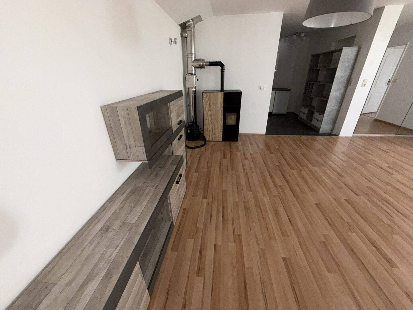 Wohnzimmer mit Laminatboden, modernem Holzofen und stilvollen Wandmöbeln in Holzoptik.