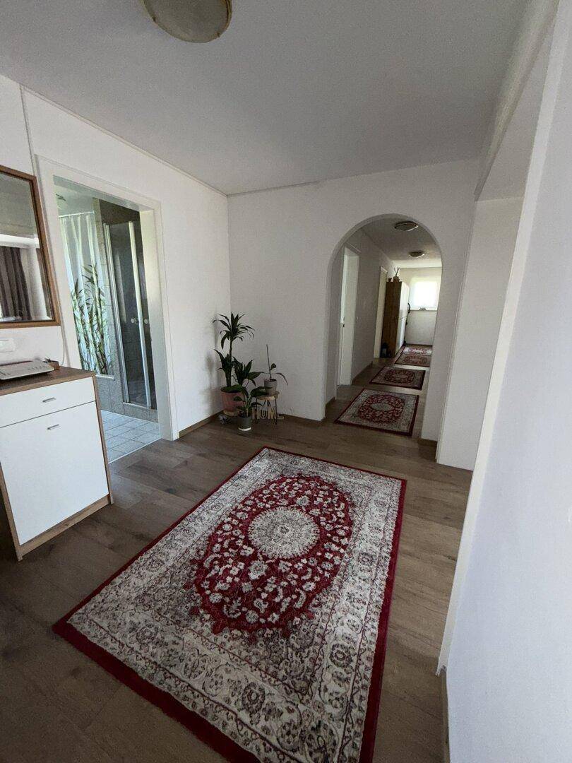 Heller Flur mit Laminatboden und traditionellen Teppichen, der zu weiteren Räumen führt.