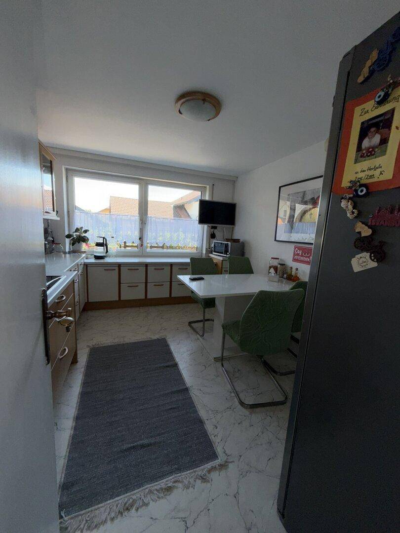 Helle Küche mit Essbereich, Fenster und weißer Einrichtung, die zum Verweilen einlädt.