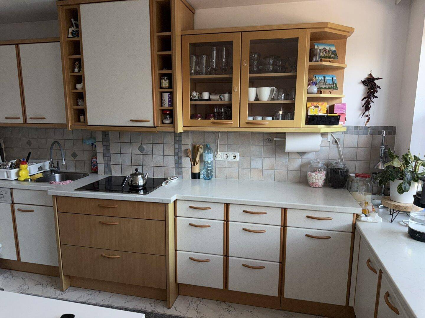 Detailansicht der Küche mit hellen Holzschränken, Fliesenrückwand und integriertem Kochfeld.