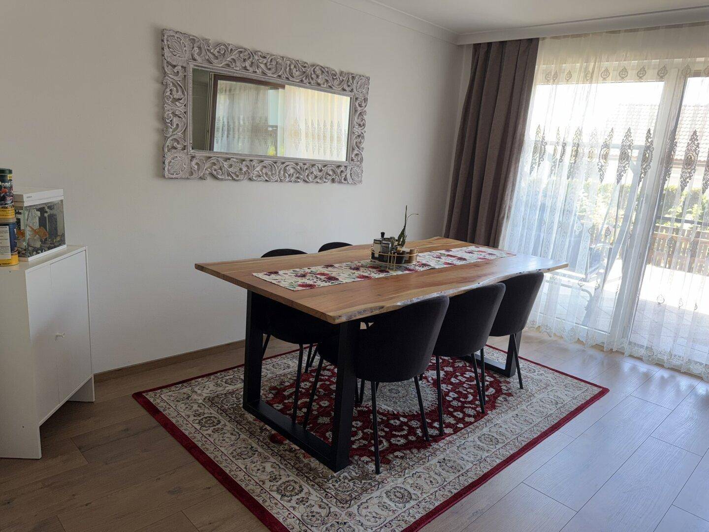Gemütlicher Essbereich mit rustikalem Holztisch, modernen Stühlen und großem Fenster zum Garten.