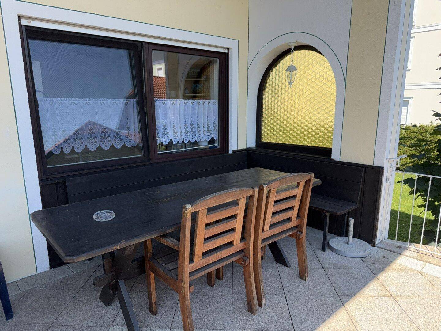 Überdachter Balkon mit Holztisch und Stühlen, ideal für Mahlzeiten im Freien.