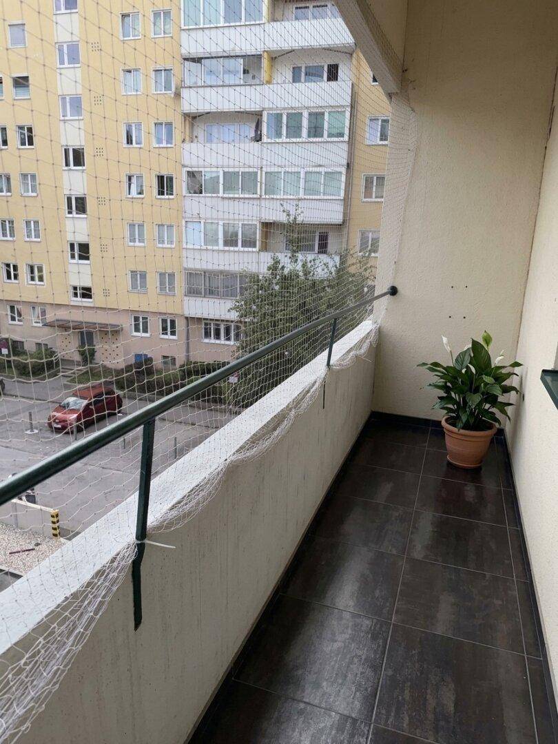 Schmaler Balkon mit Fliesenboden und Blick auf die umliegenden Gebäude.