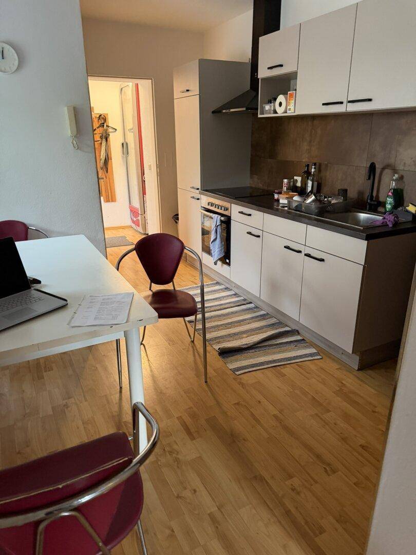 Moderne Küche mit dunkler Arbeitsplatte und Essbereich, offen zum angrenzenden Wohnraum.