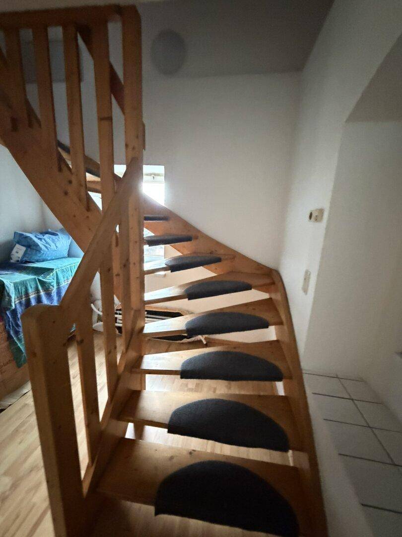 Holztreppe mit Teppichstufen führt in die obere Etage, hell und funktional.